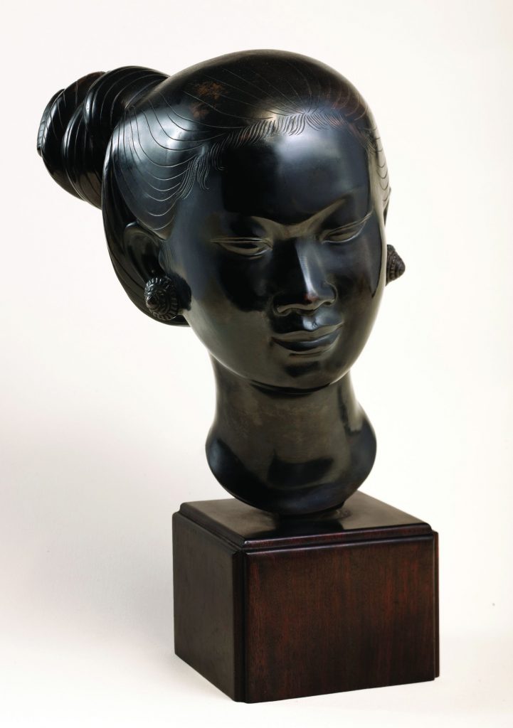 Dark polished sculpture bust of a woman's head with hair in a bun, mounted on a wooden base