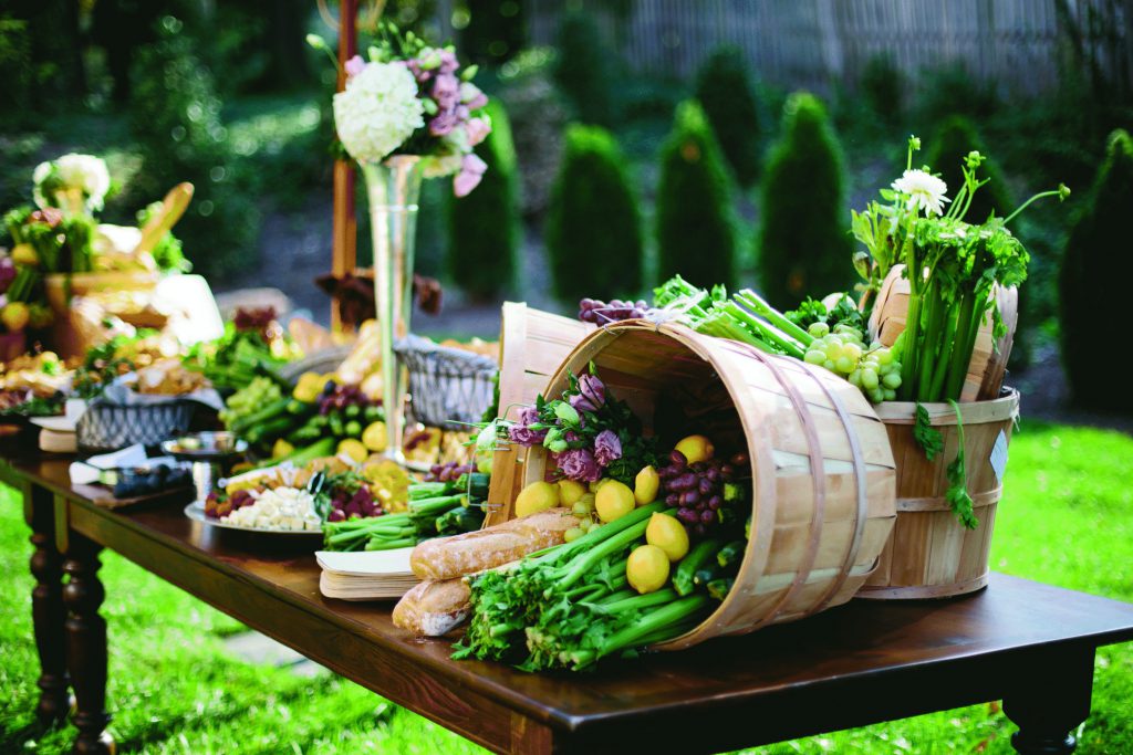 Bàn tiệc buffet với giỏ rau củ, trái cây tươi trong tiệc cưới ngoài trời