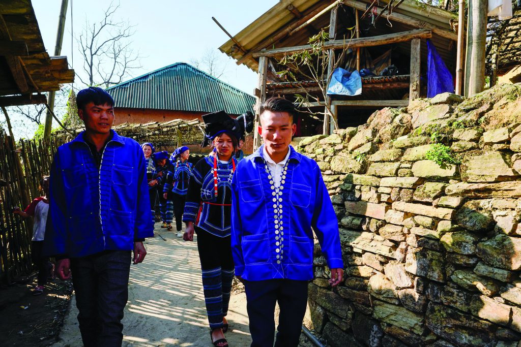 Ha Nhi wedding procession walking along a village path, wearing indigo traditional clothing