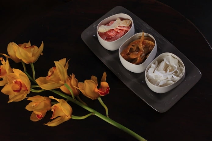 Người đàn ông trung niên mặc áo the khăn xếp chăm chú viết thư pháp trên giấy đỏ.