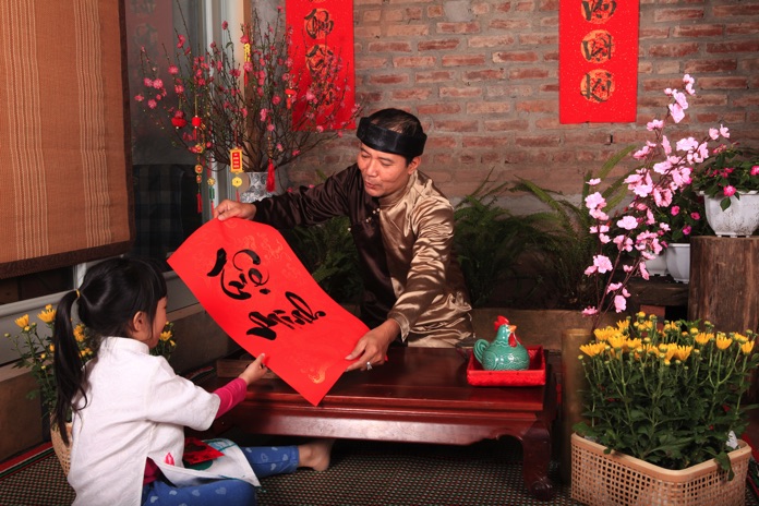 Hai bà cháu đang ngồi quây quần gói bánh chưng trên chiếu