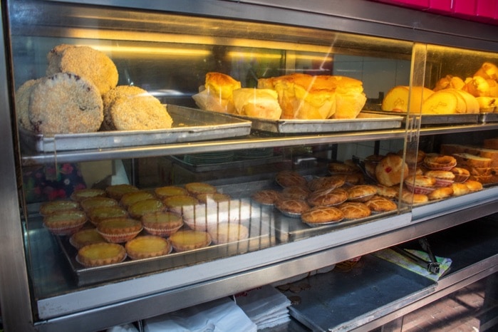 A glass display case holds rows of golden baked pastries and small tarts
