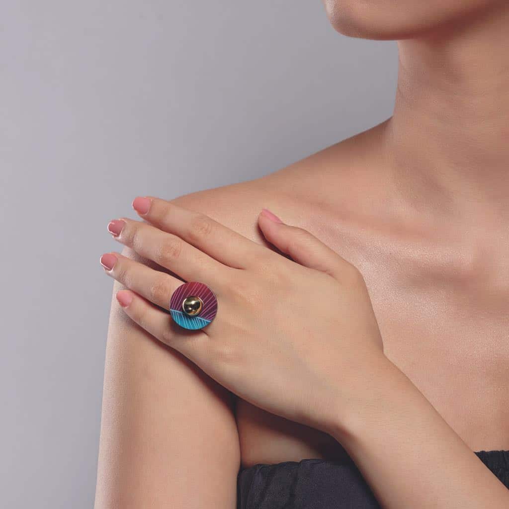 Một người phụ nữ đeo chiếc nhẫn có thiết kế độc đáo với hai nửa màu sắc tương phản đỏ và xanh