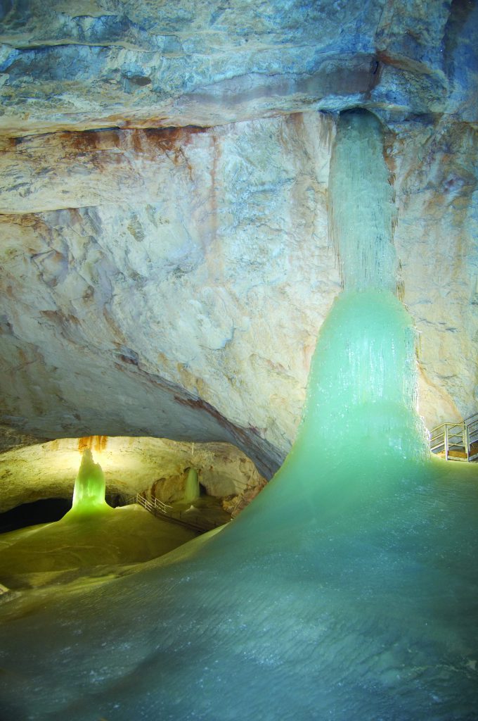 Water flows down rock formations inside a brightly lit cave