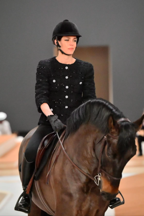 Người mẫu mặc trang phục đen cưỡi ngựa trong buổi trình diễn thời trang