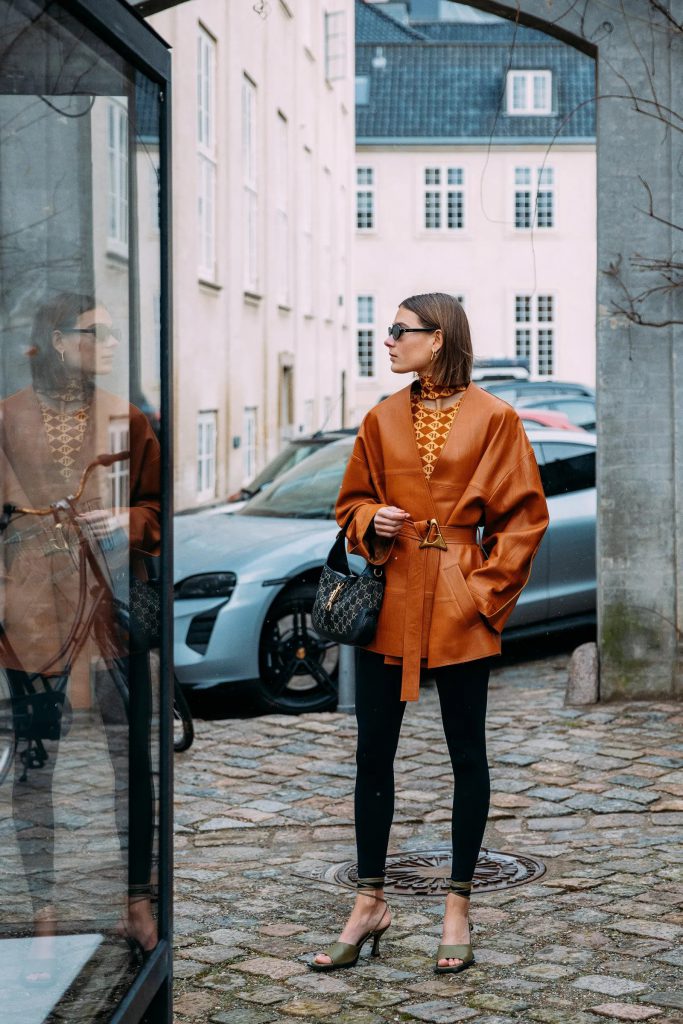 Người mẫu mặc áo khoác da màu cam và quần legging đen trên phố Copenhagen