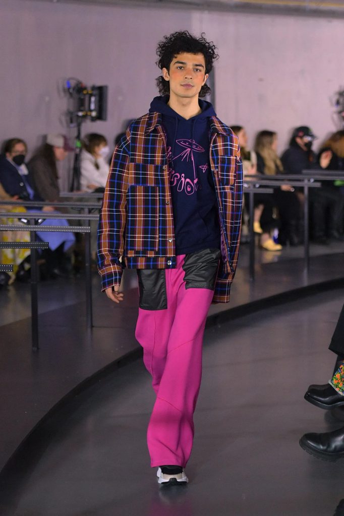 Người mẫu nam trình diễn trang phục với áo khoác kẻ sọc và quần màu hồng tại tuần lễ thời trang