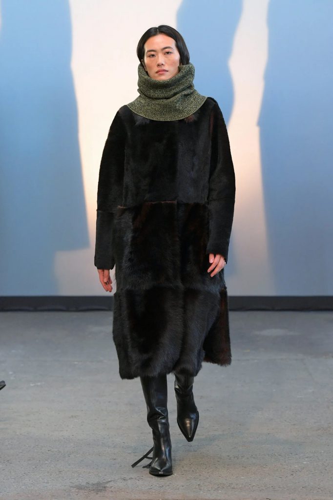 Người mẫu trình diễn áo khoác lông dài và khăn quàng cổ trên sàn diễn thời trang