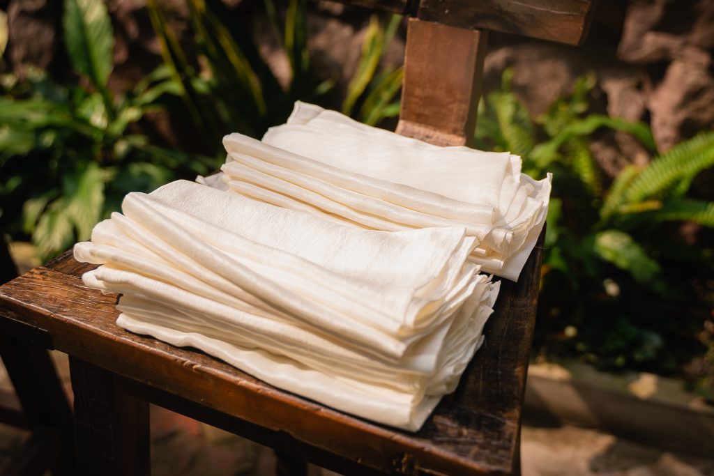 Ghế gỗ cũ chất nhiều vải trắng tinh khôi giữa khung cảnh thiên nhiên