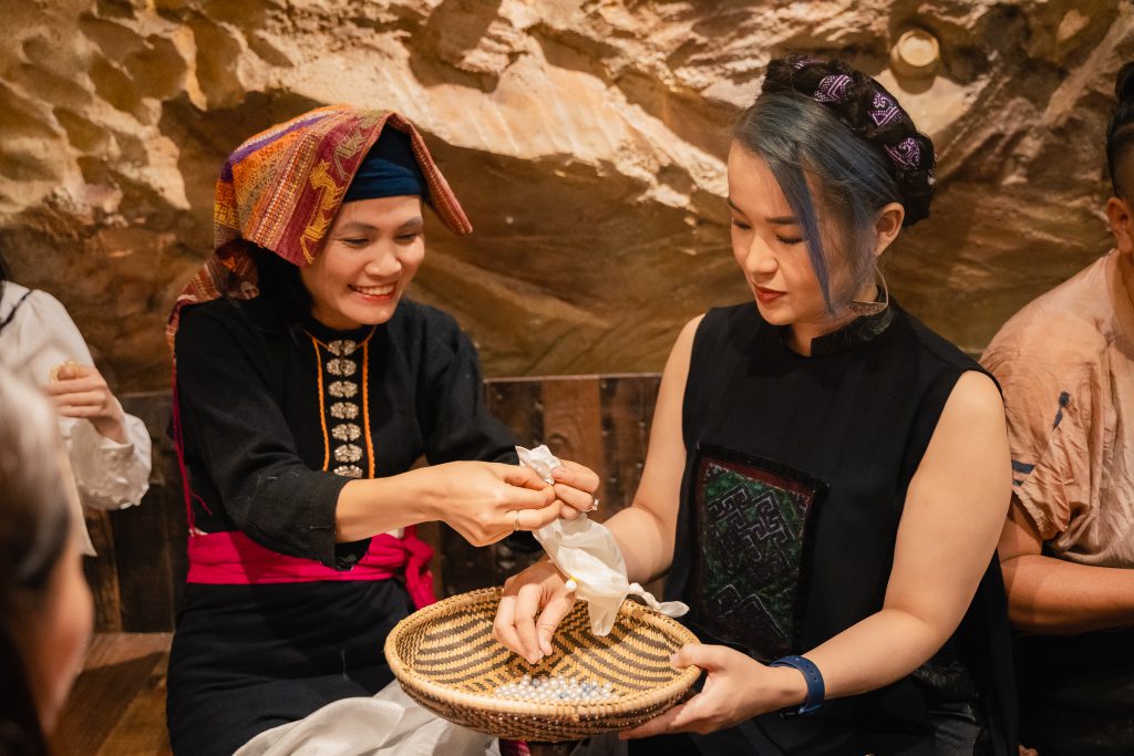 Hai người phụ nữ trao đổi sản phẩm thủ công truyền thống trong sự kiện thời trang bền vững