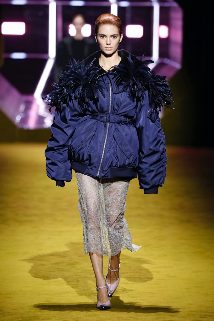 Người mẫu trình diễn áo khoác bomber xanh đậm và váy xuyên thấu trên sàn diễn Prada