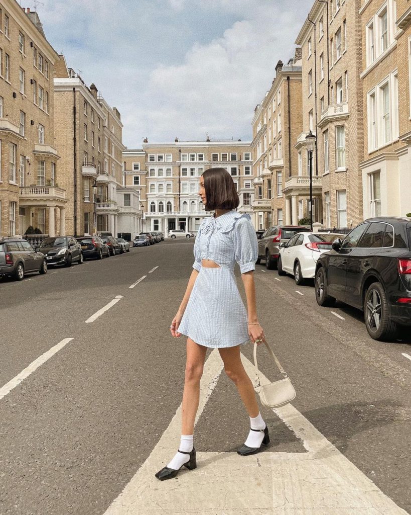 Cô gái mặc váy ngắn đi bộ trên vạch kẻ đường ở phố London