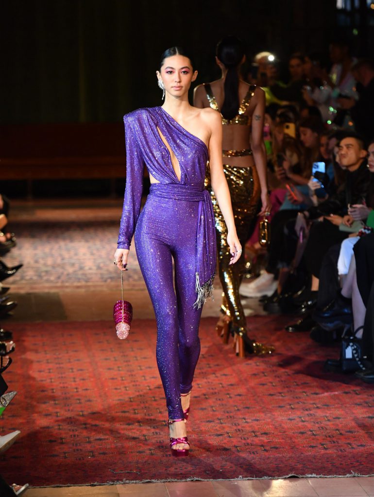 Người mẫu trình diễn bộ đồ liền thân màu tím lấp lánh trên sàn catwalk thời trang