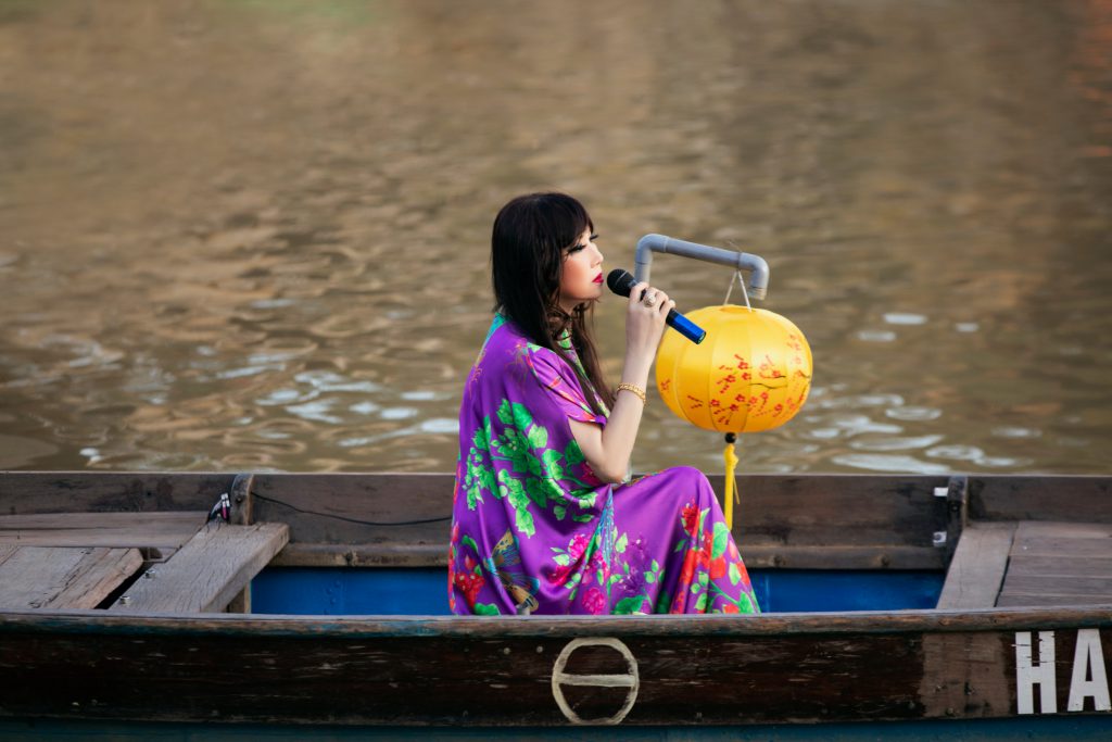 Cô gái hát trên thuyền với đèn lồng vàng rực rỡ bên dòng sông