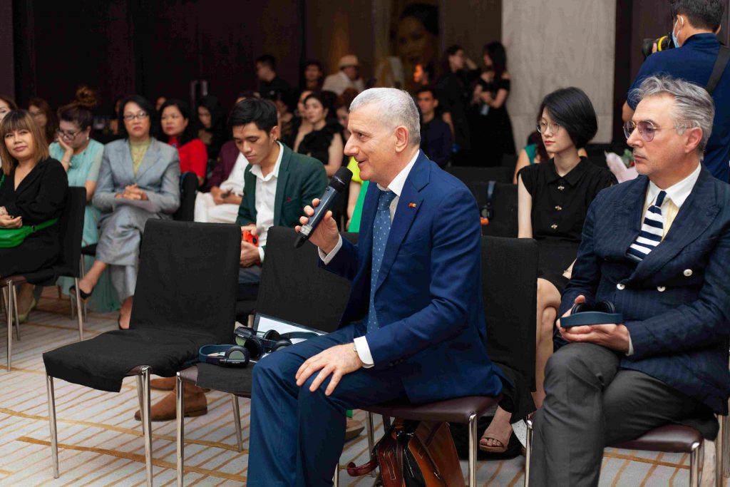 Một người đàn ông lớn tuổi đang phát biểu tại một sự kiện với nhiều người tham dự