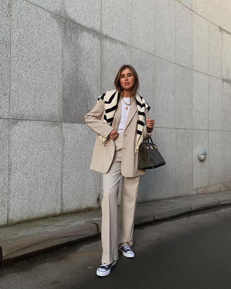 Cô gái mặc áo khoác dài và quần ống rộng đi giày thể thao trên phố