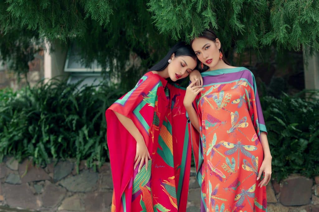 Hai cô gái mặc váy họa tiết sặc sỡ tạo dáng bên cây xanh