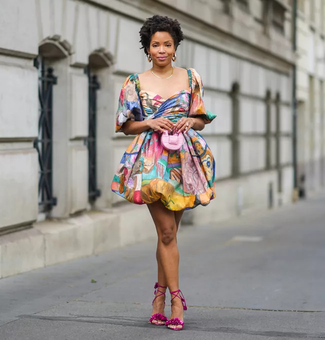 Người phụ nữ mặc váy họa tiết sặc sỡ và giày cao gót hồng trên phố