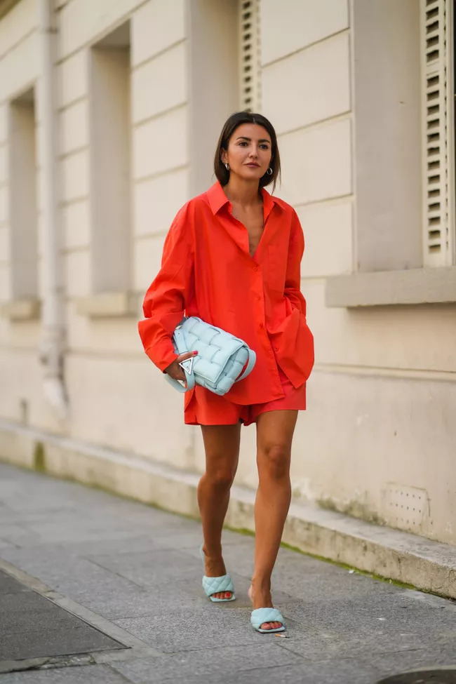 Cô gái mặc áo sơ mi dáng rộng màu cam và đi dép lê trên phố