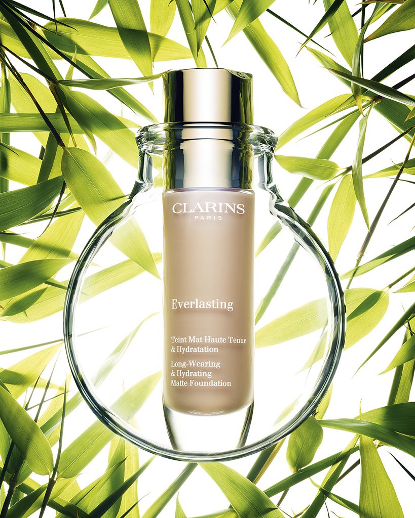 Chai phấn nền Clarins Everlasting nổi bật giữa tán lá xanh tươi mát
