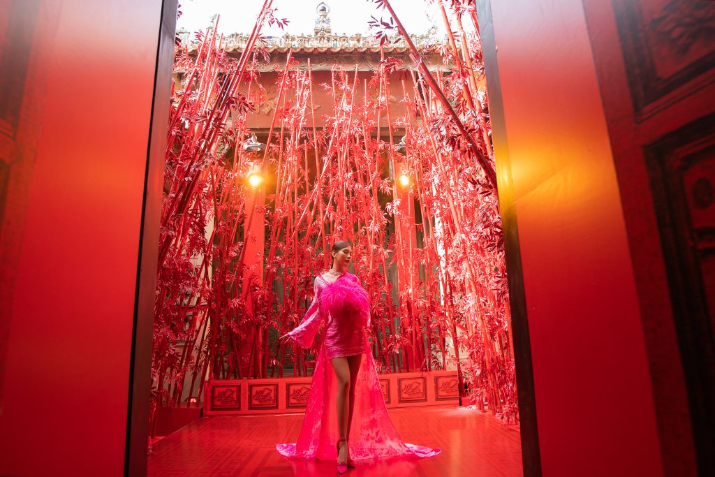 Người mẫu diện váy hồng nổi bật giữa không gian kiến trúc truyền thống nhuộm đỏ rực rỡ