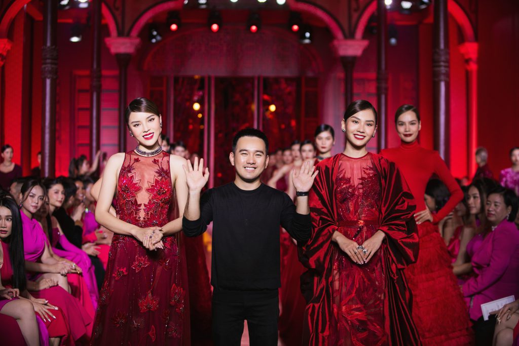 Nhà thiết kế Lê Thanh Hòa cùng hai người mẫu trên sàn diễn thời trang với trang phục màu đỏ rực rỡ