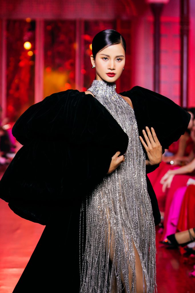 Người mẫu trình diễn váy dạ hội lấp lánh và áo choàng đen sang trọng