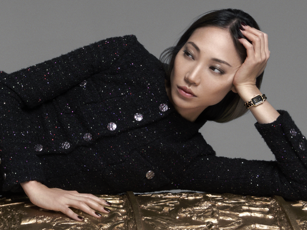 Người phụ nữ mặc áo khoác đen thanh lịch đeo đồng hồ vàng trên tay