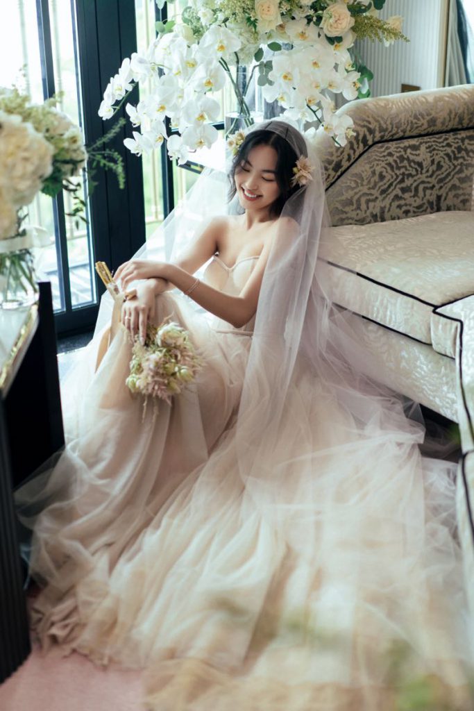 Cô dâu xinh đẹp mặc váy cưới đang cầm bó hoa và nhìn xuống đầy hạnh phúc