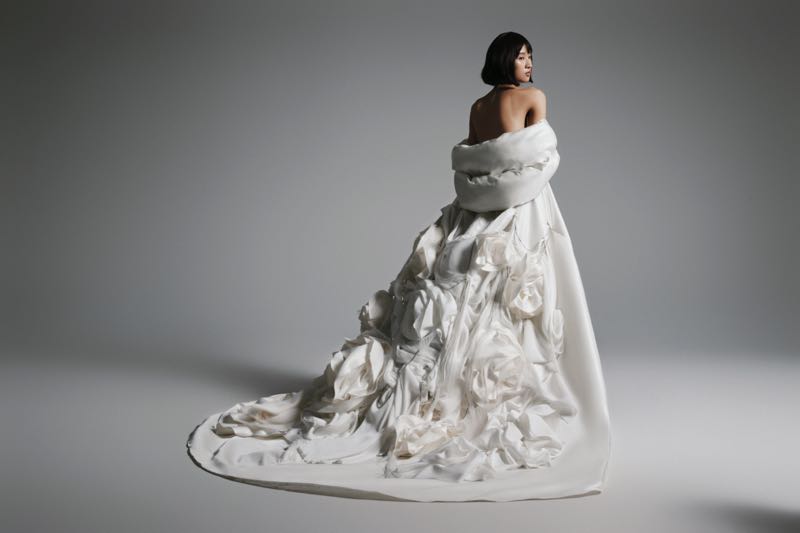 Người mẫu diện chiếc váy cưới trắng tinh tế với phần đuôi váy xếp nếp hoa lớn