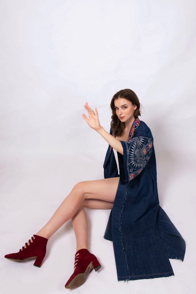 Người mẫu trẻ ngồi tạo dáng với áo khoác denim thêu họa tiết thổ cẩm tinh xảo