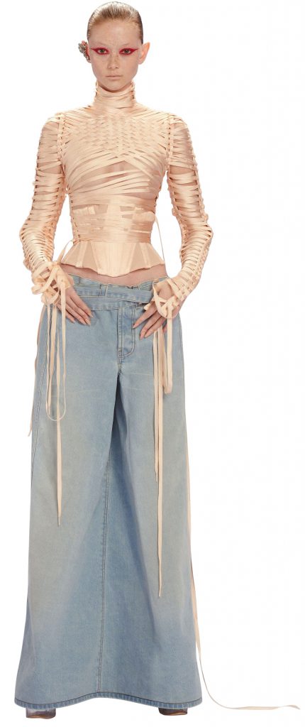 Người mẫu trình diễn trang phục cao cấp gồm áo dài tay và quần jean ống rộng màu xanh nhạt