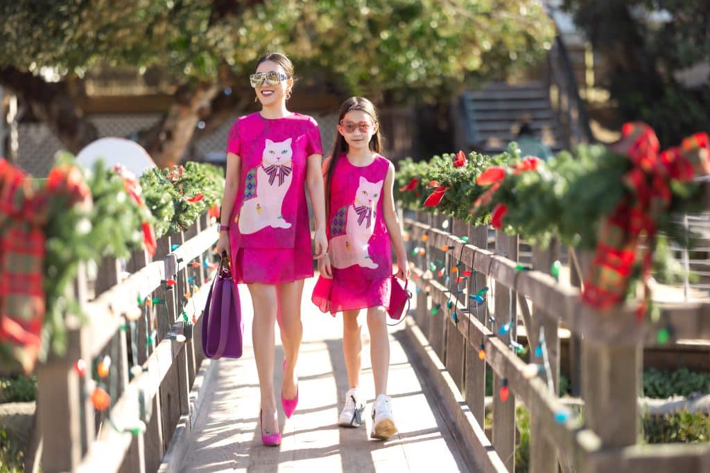 Mẹ và bé diện trang phục màu hồng rực rỡ cùng họa tiết mèo đáng yêu trên cầu gỗ