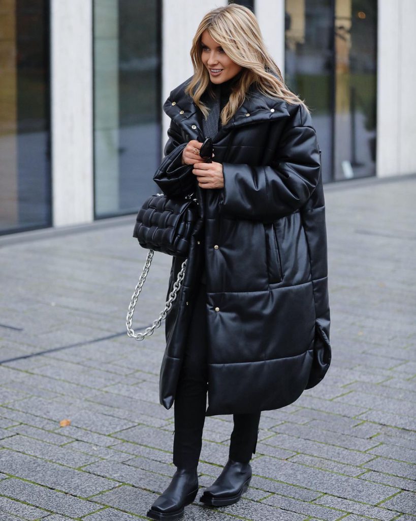 Cô gái mặc áo phao đen dài dáng rộng cùng quần legging và ủng đen