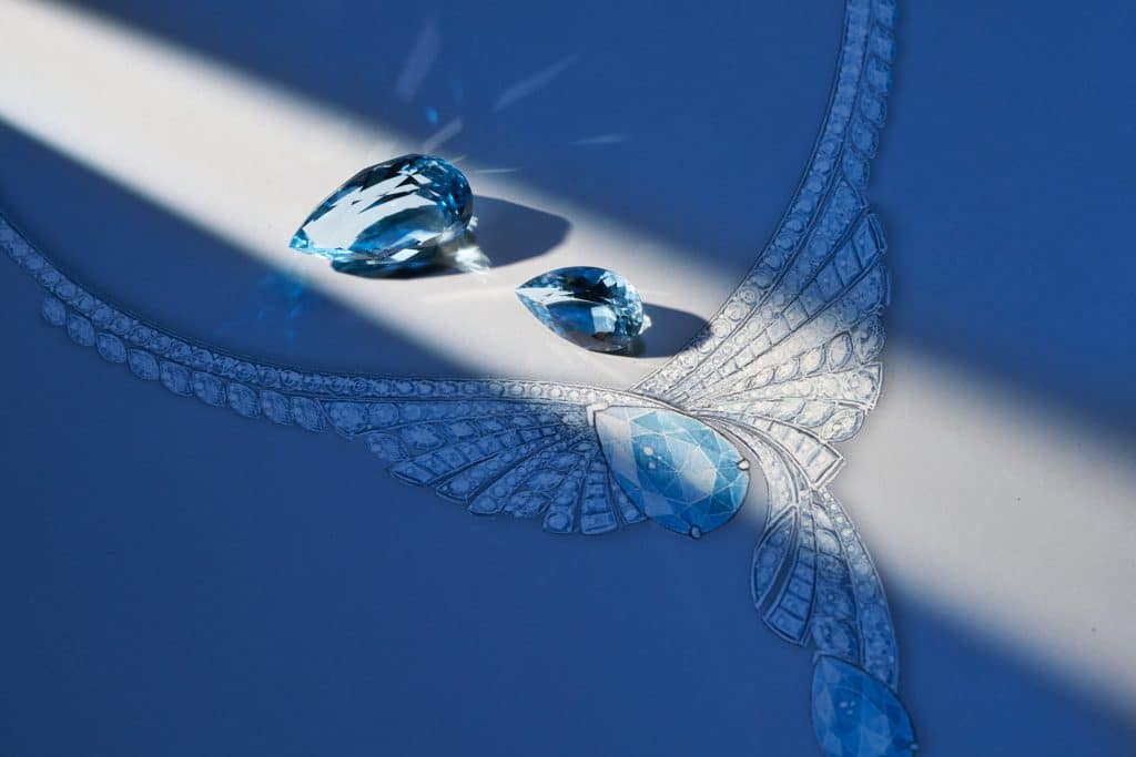 Đá quý màu xanh ngọc bích lấp lánh bên cạnh bản phác thảo thiết kế trang sức tinh xảo