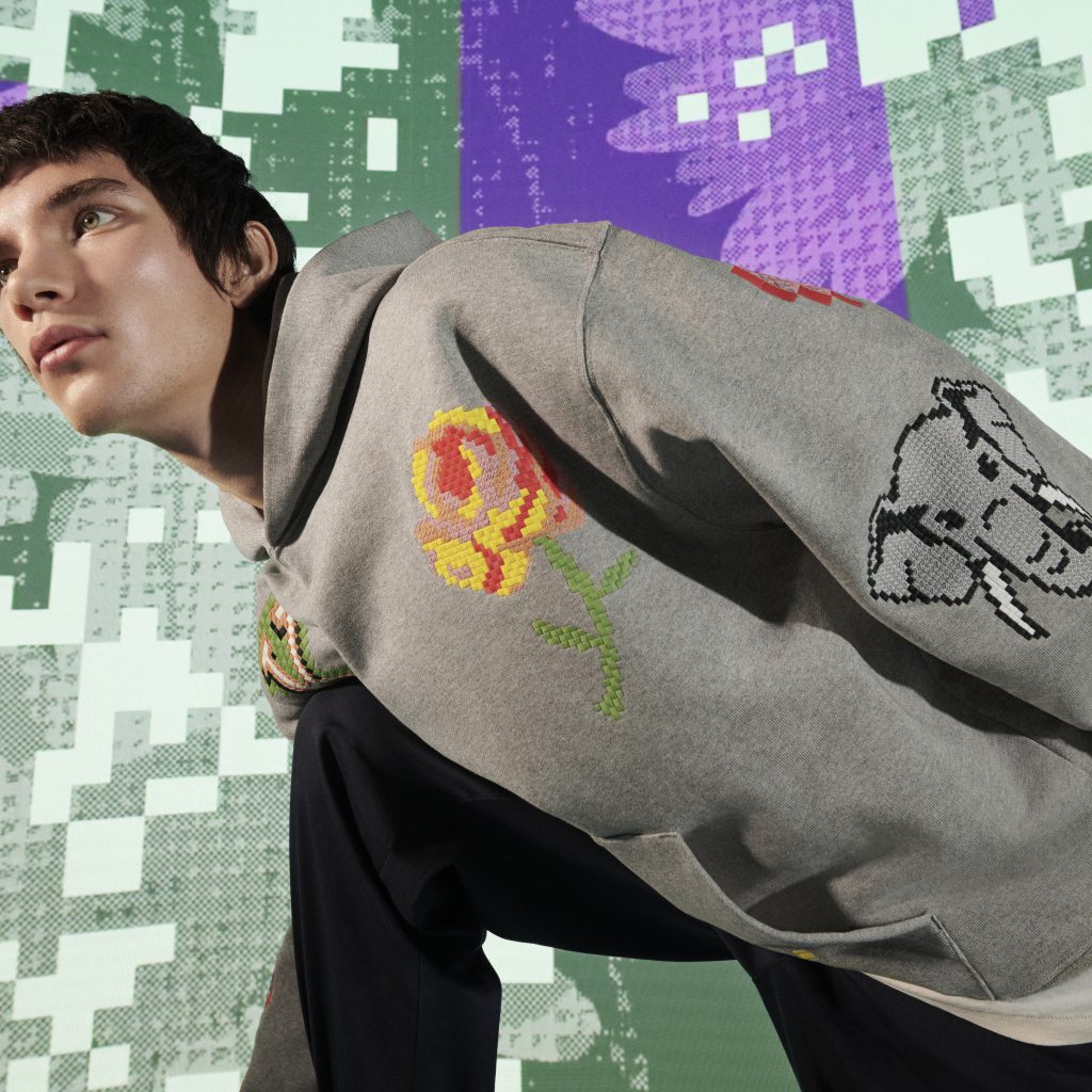 Người mẫu mặc áo khoác xám thêu hoa hồng nổi bật trên nền họa tiết