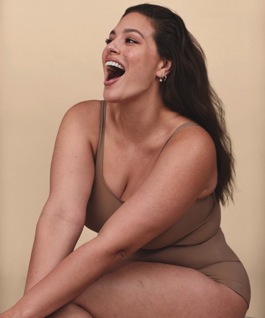 Người phụ nữ tự tin cười rạng rỡ mặc đồ lót màu be trên nền vàng nhạt