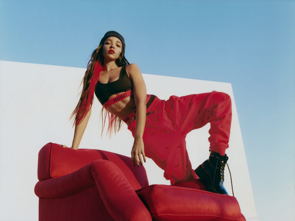 Người mẫu trẻ trung tạo dáng trên ghế sofa đỏ trong trang phục HUGO Xuân/Hè 2023