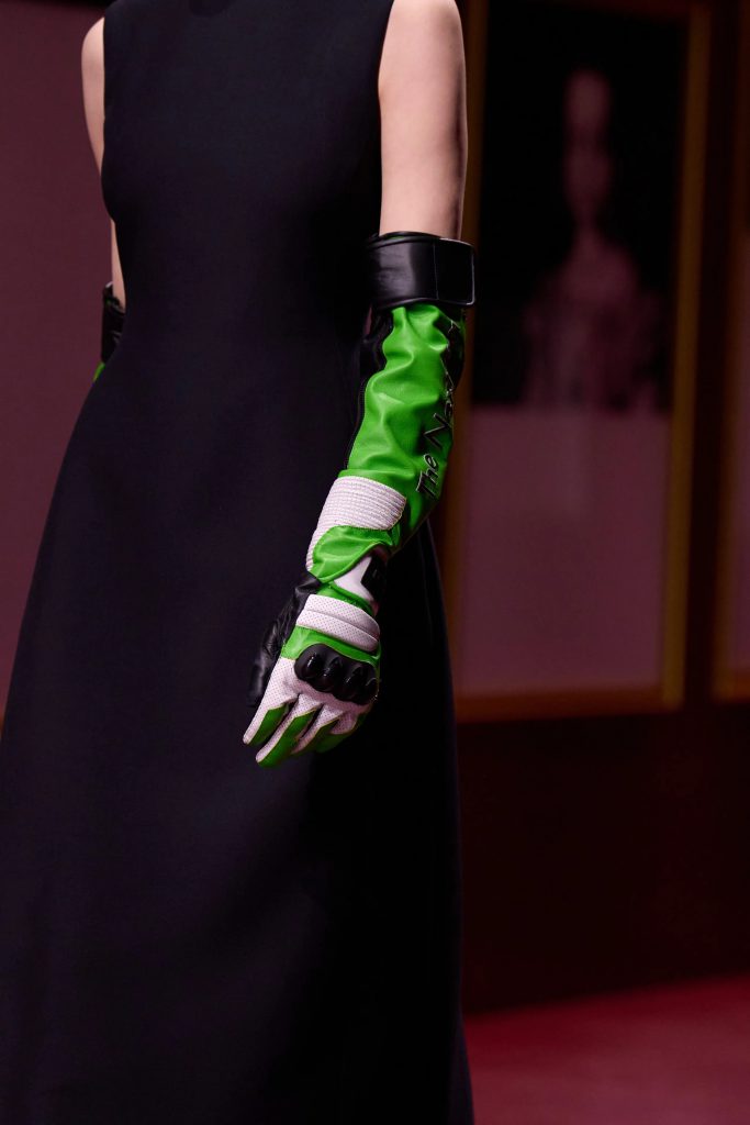 Người phụ nữ mặc váy đen đeo găng tay dạ hội xanh lục dài tới khuỷu tay