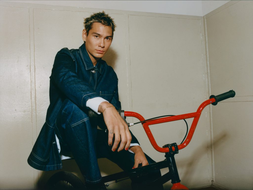 Người đàn ông trẻ mặc áo denim ngồi trên xe đạp BMX màu đỏ