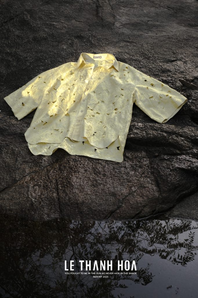 Áo sơ mi ngắn tay màu vàng nhạt với họa tiết cắt xẻ độc đáo trên nền đá đen