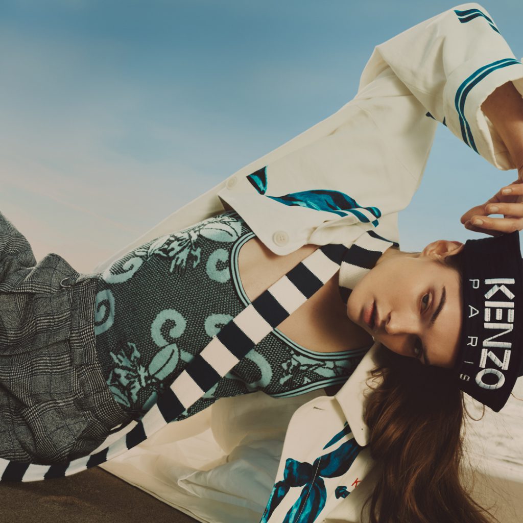 Người mẫu nằm nghiêng mặc trang phục họa tiết sọc và họa tiết rồng KENZO Paris dưới bầu trời xanh