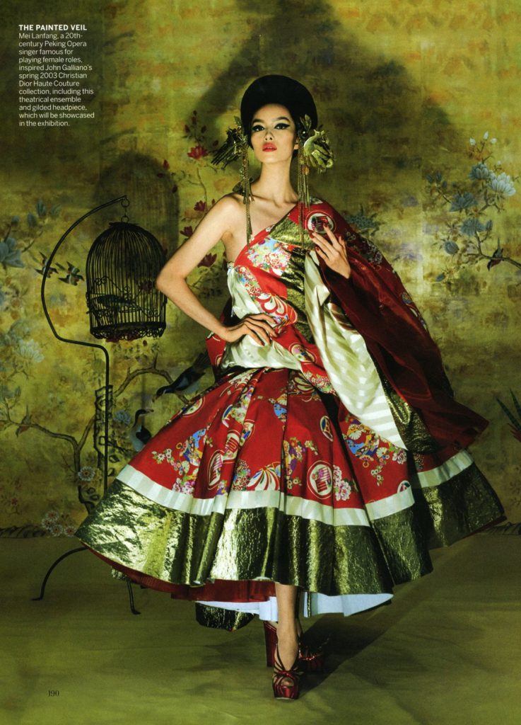 Người mẫu mặc váy đỏ trắng lộng lẫy tạo dáng bên lồng chim và phông nền hoa lá