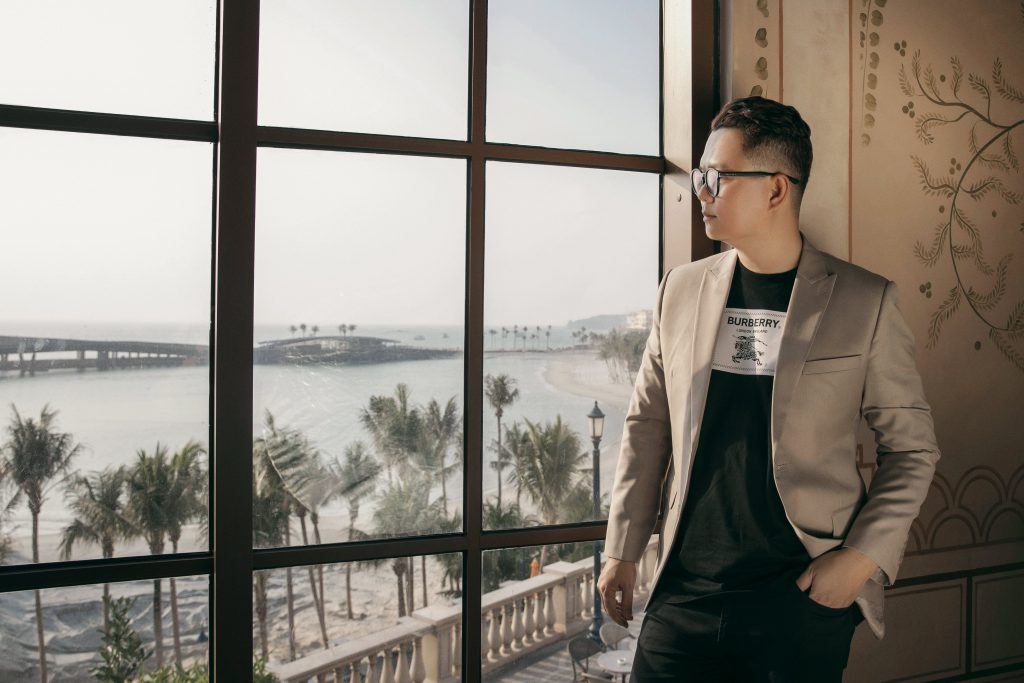 Người đàn ông mặc vest lịch lãm nhìn ra biển qua khung cửa sổ lớn