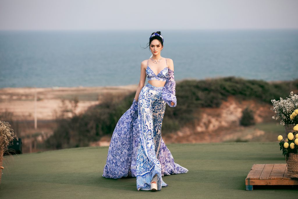 Người mẫu trình diễn trang phục họa tiết hoa xanh nổi bật trên thảm cỏ hướng biển