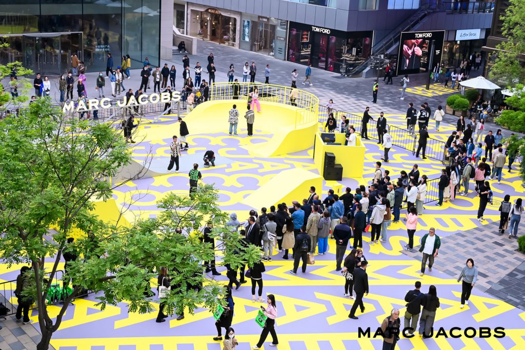 Đám đông người tập trung trên quảng trường được trang trí họa tiết monogram Marc Jacobs nổi bật