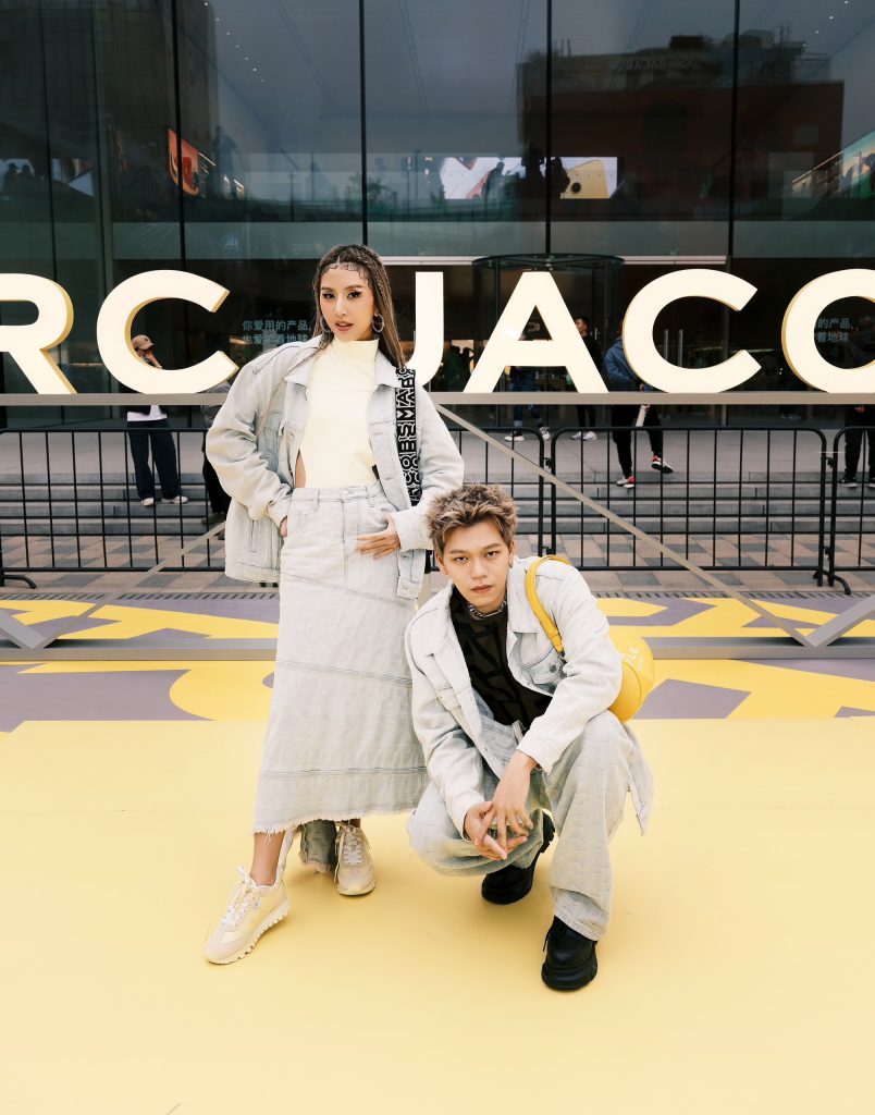 Hai người mẫu trẻ trung tạo dáng trước tòa nhà có logo Marc Jacobs lớn