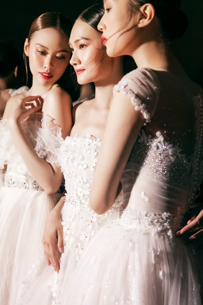 Ba người mẫu xinh đẹp diện váy trắng lộng lẫy đang chuẩn bị cho buổi trình diễn thời trang