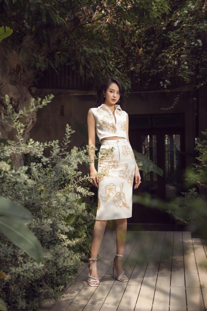 Hoa hậu Thanh Thủy mặc trang phục trắng tinh tế giữa khung cảnh cây xanh mát mẻ