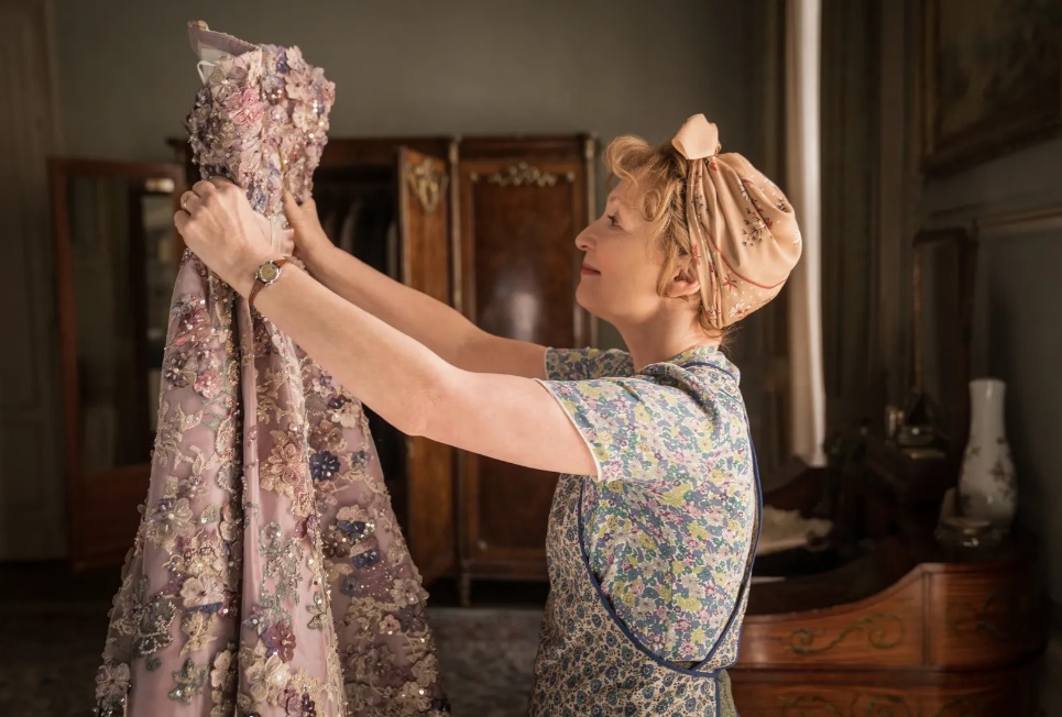 Người phụ nữ đang xem xét một chiếc váy lộng lẫy trong căn phòng trang trí cổ điển